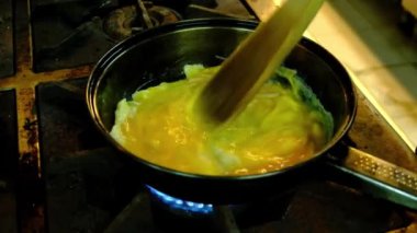 Şef tavada omlet yumurtalarını kızartıyor.