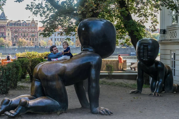 Prag, Tschechische Republik - 10. September 2019: Vater spielt mit Baby auf einer riesigen Bronzestatue von David Cerny — Stockfoto