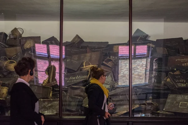 Oswiencim, Polen-September 21, 2019: turister deltar i en guidad tur inne i Auschwitz byggnader, i ett galleri med tillhörigheter av prisioners — Stockfoto