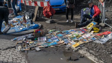 Krakow, Polonya-21 Eylül 2019: Man Krakow sokak bit pazarında su birikintisi kenarında kitap bir sürü satıyor.