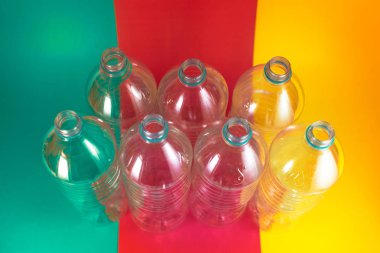 7 boş ve geri dönüşümlü plastik su şişeleri bir paket, hiçbir kapaklar, mavi mühür, renkli canlı deniz yeşili, şarap kırmızı ve sarı arka plan. Yeniden kullanım, Çevre Dostu, Çevre konsepti. Üstte görüntü.