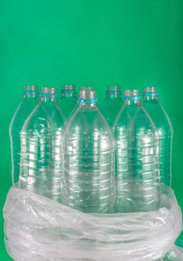 8 boş ve geri dönüşümlü plastik su şişeleri bir paket Verticam görüntü, hiçbir kapaklar ile, mavi mühür, plastik bir torba içinde, renkli bir deniz yeşili arka plan üzerinde. Yeniden Kullanım, Çevre Dostu, Çevre konsepti.