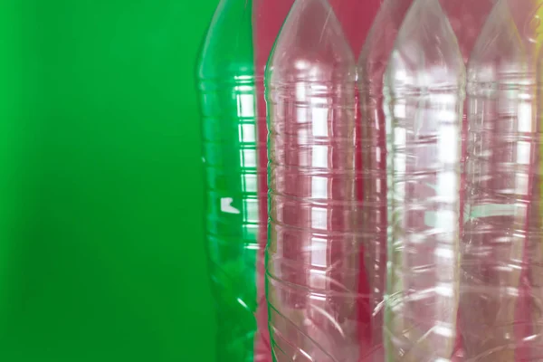 Un paquet de bouteilles d'eau en plastique vides et recyclables, sur un fond vert vif coloré et rouge vin. Réutilisation, respectueux de l'environnement, concept d'environnement. Texture plastique, vue latérale . — Photo
