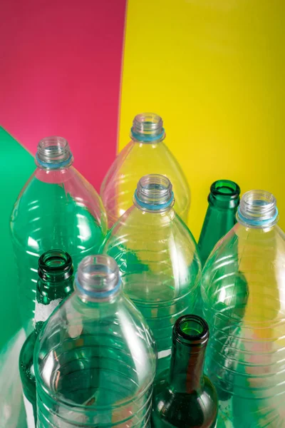 Ensembles de bouteilles en verre vides et de bouteilles en plastique sans étiquette sur un fond vert vif, rouge vin et jaune. Réutilisation, Respectueux de l'environnement, Environnement, Conservation, Durable et Ressources — Photo