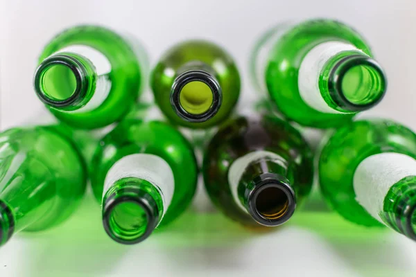 Vue de dessus d'un paquet de bouteilles vides de bière et de vin en verre vert et brun, avec des étiquettes déchirées sur un fond blanc. Réutilisation, acoholisme, recyclage et concept de fête . — Photo