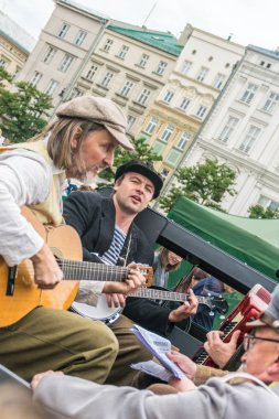 Krakow, Polonya - 23 Eylül 2018: Krakow ana meydanında antika bir kamyonetin üstünde bir grupla şarkı söyleyen ve gitar çalan köylüler gibi giyinmiş müzisyenler