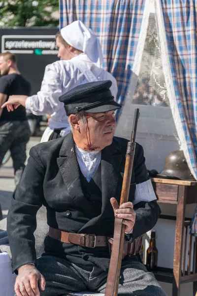 Cracovia, Polonia - 23 de septiembre de 2018: Varón herido vestido con uniformes polacos de la Primera Guerra Mundial, sosteniendo una escopeta entre los turistas en la plaza principal de Krakows — Foto de Stock