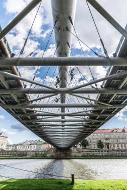 Krakow, Polonya - 23 Eylül 2018: Polonya'daki Kladka Ojca Bernatka köprüsünün altından manzara, Krakow, gün ışığında Vistule nehri üzerinde, arka planda çim ve binalarla