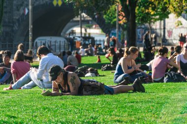 Berlin, Almanya - 26 Eylül 2018: Çimlerin arasında yatan ve James Simon Park'ta yazan bir adama odaklanarak dinlenen dövmeli adam, Müze Adası'nın yanında ve Katedrali'nin arkasında