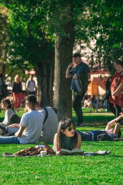Berlin, Almanya - 26 Eylül 2018: James Simon Parkı'nda çimenlerin arasında yatan güneş gözlüklü bir kadının dikey görünümü, Müze Adası'nın yanında ve Berlin Katedrali'nin arkasında