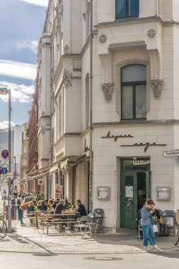 Berlin, Almanya - 26 Eylül 2018: Kız, Berlin'in merkezindeki bir restoranın masalarında oturan insanlarla işlek bir caddenin kaldırımındaki bazı binaların önünde telefonunu kontrol ediyor