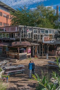 Berlin, Almanya - 26 Eylül 2018: Holzmarkt'ın avlusuna ait sıra dışı bir binanın yakınında fotoğraf çeken turistler ve Kreuzberg, Friedrichshain ve Mitte arasında açık keyif alanı