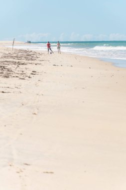 Bahia, Brezilya - 27 Haziran 2019: Porto Seguro'daki yerliler plajında yaz tatili sırasında mavi denize yakın tropik bir ortamda futbol yeteneklerini sergileyen aktif çocuklar