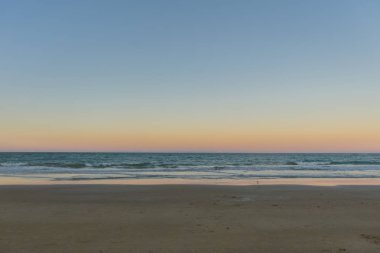 Boş Trancoso plajda okyanus tarafından sessiz ve pembe gün batımı, bir degrade renkli silueti ile, sakin mavi dalgalar, ve kum gökyüzünü yansıtan su, Trancoso, Porto Seguro, Bahia