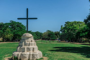 Dairesel beton türbe Trancoso, Porto Seguro, üzerinde bir haç ile beyaz boyalı, sınırları ve çocuklar arka bir top ile oynayan birçok ağaç ile bir çim alanı önünde