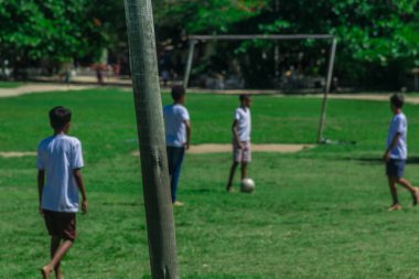 Beyaz giyinmiş küçük yerel çocuklar ve Porto Seguro, Bahia, bir turizm dönüm noktası de, Trancoso Quadrado bir köyde bazı evlerin yakınında basit bir netless gol ile bir çim alanda futbol oynarken
