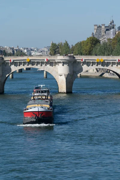 Coda di barche rosse che attraversano un ponte con architettura classica sulla Senna a Parigi, Francia con alberi ed edifici della città sullo sfondo durante il giorno — Foto Stock