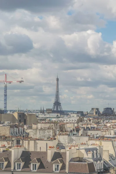 Romantica veduta dell'architettura dei tetti degli appartamenti e del commercio di Parigi, con la famosa torre eiffel e una gru a torre sullo sfondo durante una giornata nuvolosa — Foto Stock