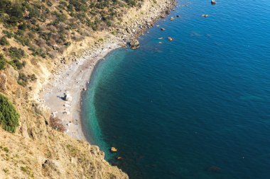 Yukarıdan yüzen insanların olduğu sahilin manzarası. Sahilde tatil yapan insanların güzel panoramik manzarası. Turkuaz parlak deniz suyu. Yaz turizm sezonu.