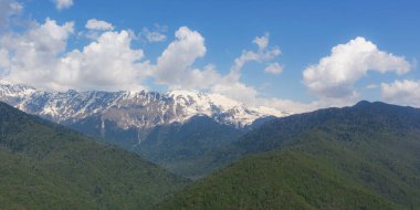 Kar ve orman manzaralı dağlar. Nisan ayında Kafkaslar 'ın dağ sırasının güzel manzarası. Bahar dağları. Uzun, dar, doğal bir afiş. Rusya 'ya seyahat.