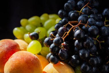 Şeftali ve üzümler yakın plan. Meyvenin doğal ışıktaki makro fotoğrafçılığı. Olgun sulu şeftaliler. Tatlı, büyük üzümler. Meyve suyu için meyve suyu. Tabakta taze tropikal meyve.