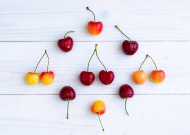 Beyaz ahşap arka plan manzaralı kiraz kompozisyonu. Yaz havasının yerleşim konsepti. Lezzetli kiraz meyveleri yakın plan..