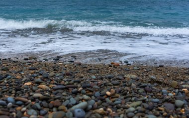 Çakıl taşı plajı ve turkuaz su. Su ve çakıl taşı dokusu. Yukarıdan temiz ve berrak su manzaralı sahil.