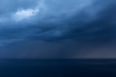 Denizin üzerinde yağmur bulutları. Güzel mavi Cumulus bulutları. Bulutlu ve tehditkar bir manzara. Korkunç bir fırtına uyarısı. Denizin üzerinde yağmur.