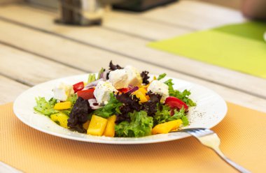 Yazlık kafede beyaz tabakta Yunan salatası. Vejetaryen yemeği. Zeytin, mor soğan ve peynir. Bir kafede hafif atıştırmalıklar. Yaz menüsü. Doğal ışık.