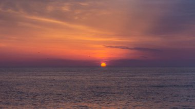 Denizin üzerinde güzel turuncu gün batımı. Güneş ufuktan batıyor. Rahatlatıcı deniz manzarası. Gökyüzünün ve deniz suyunun mor tonları. Karadeniz üzerinde gün batımı. Doğal arkaplan.