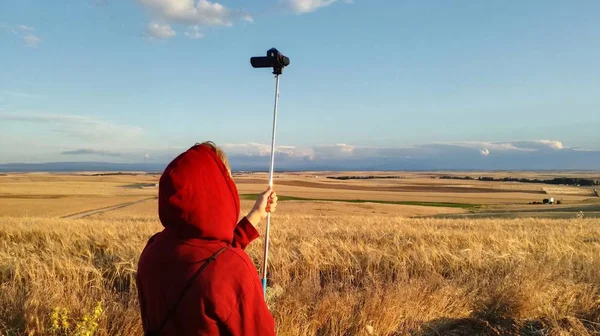 Genç çocuk İspanyol tarım arazisinin videosunu kaydediyor. Buğday ve arpa ile ekilen tarlalar, gözün ufukta görebildiği kadar büyür. Avrupa kırsalında bir yaz öğleden sonra sakin gökyüzü.