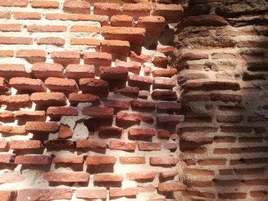 Katı kırmızı kil tuğla çok eski. Eski ve gerçek duvar. Uzun tuğlanın korunduğu, montaj ve bağlantı malzemesinin aşındığı duvar.