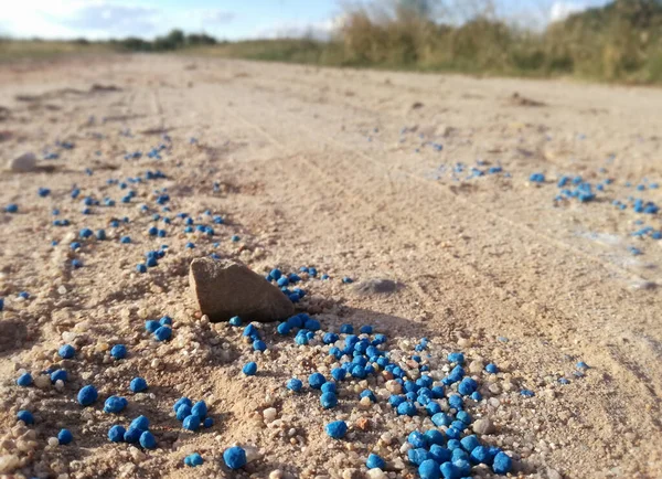 Winter fertilizer of cereals in the agricultural industry. Nitrogen, phosphorus and potassium as nutrients to strengthen the grain. Manure balls spilled accidentally on the rural road to the orchard.