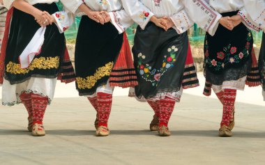 Dans eden kızlar. Geleneksel kostümlü insanlar Bulgar halk dansları yapıyor. Halk dansları için geleneksel ayakkabı, çorap ve kostümlü kadın bacakları yakın plan..