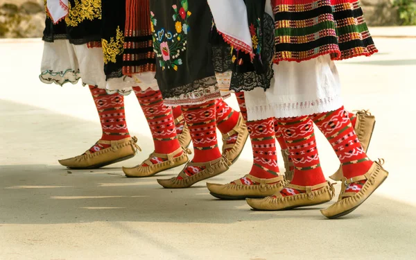 Bulgarian folklore. Girls dancing folk dance. People in traditional costumes dance Bulgarian folk dances. Close-up of female legs with traditional shoes, socks and costumes for Bulgarian folk dances.