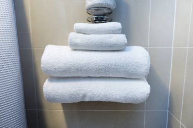 stack of various sizes of white towels at a hotel. bathroom