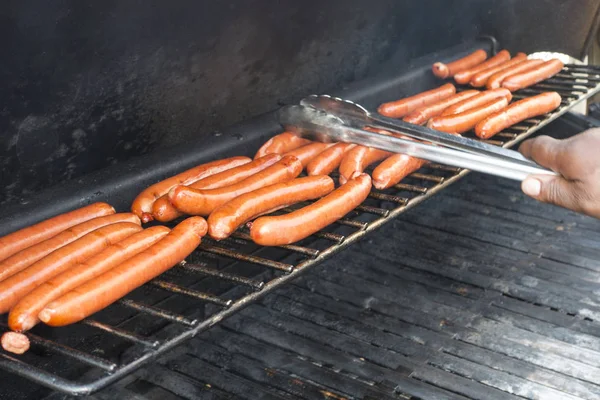 American hotdogs bing cooked on an outside propane grill by a ma — Stock Photo, Image