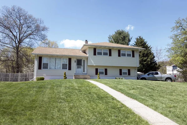 yeşil çim ve koyu pencere tonları ile banliyö ev.