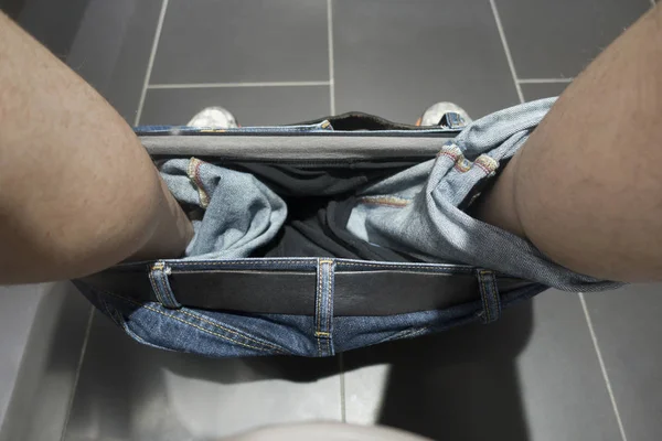 Man using the toilet with blue jeans down — Stock Photo, Image