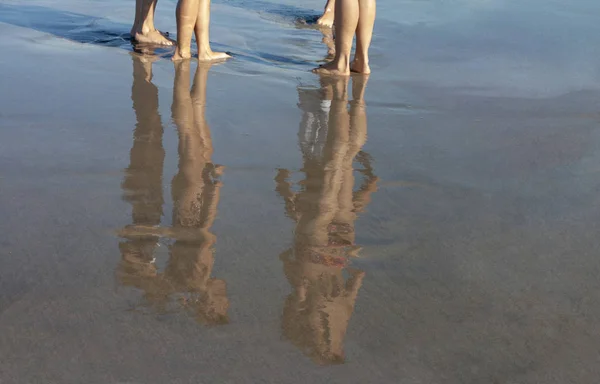Unga badare i Bad dräkter reflektion på färsk våt sand — Stockfoto