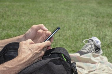 bir par bir battaniye üzerinde oturan bir cep telefonu kullanarak adam yakın