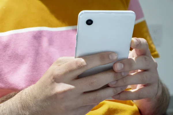 Im Freien junger Mann am Handy mit beiden Händen SMS hell c — Stockfoto