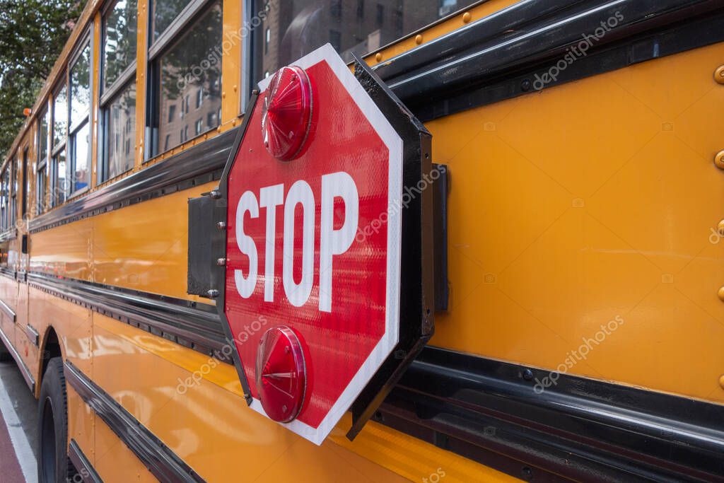A red stop sign with lights on the side of a yellow school bus.