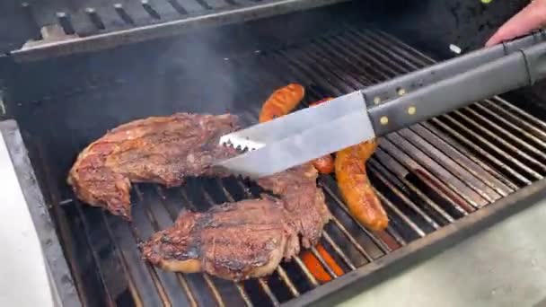 Homem Camisa Verde Com Línguas Metálicas Cozinhando Estacas Salsichas Seu — Vídeo de Stock