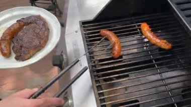 Yaşam tarzı yaz adamı propan gazı ızgarasında kazık ve sosis pişiriyor metal dilleri deliğe sokuyor.