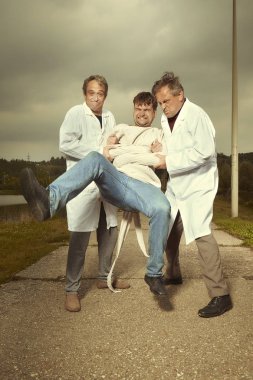 İki büyük retro paramedik ucube avcıları tıbbi kat deli gömleği için deli adam alıcı olarak