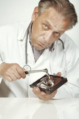 Hard disc drive doctor checking condition of opened 3,5'' drive with hammer clipart