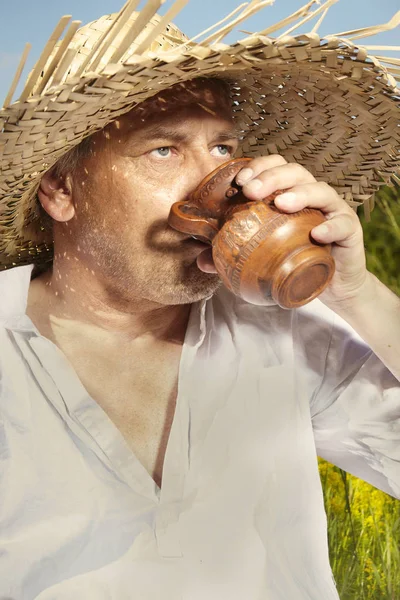 Village natural country man on summer meadow drinking after mowing grass