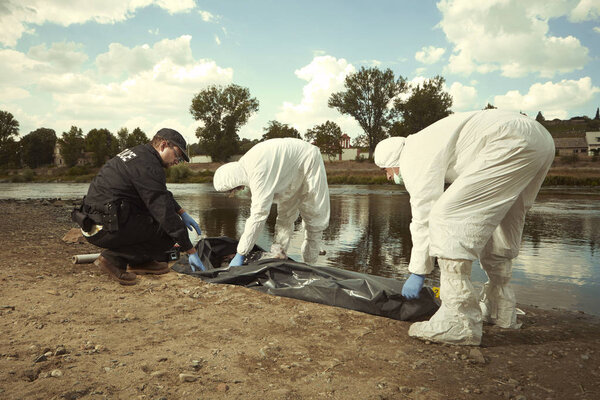 Woman found drowned on river bank in city placed in body bag for transportration