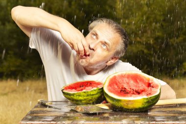 Adam yenileme yaz yağmurlu günde masaya karpuz yeme